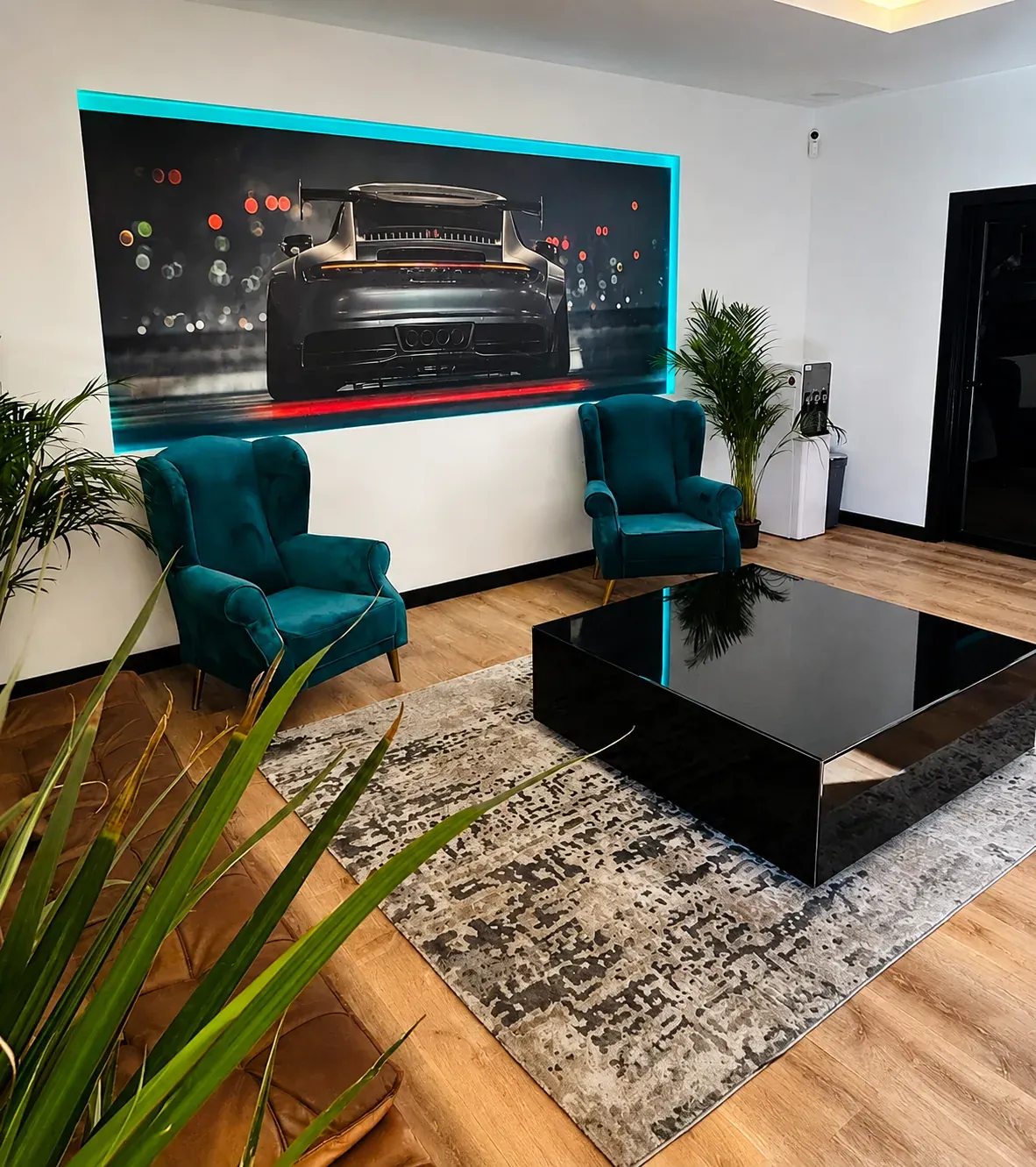 Sala de espera de Faster Garage con sillones y cuadro de un Porsche 911